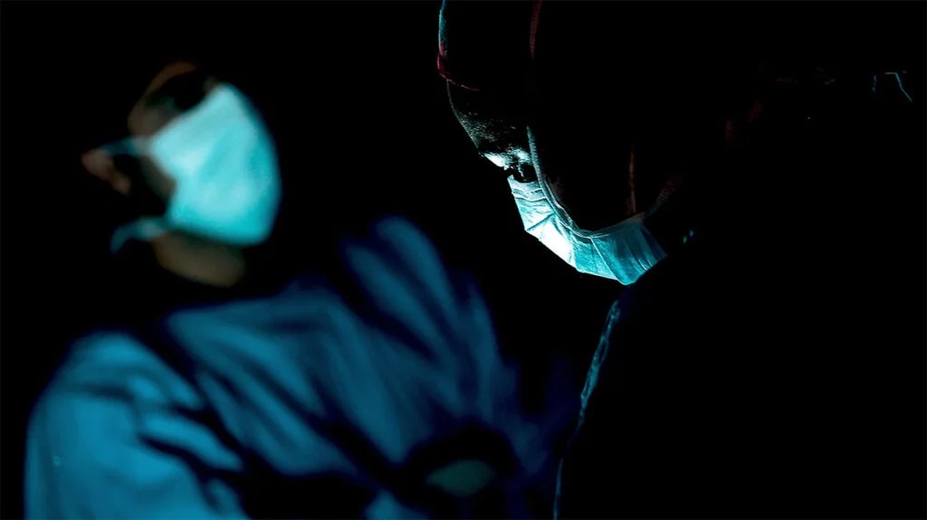 A surgeon operates in a darkened room