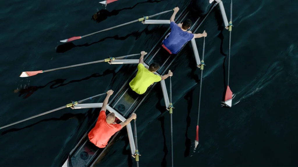 Overhead view of 3 males rowing across a river
